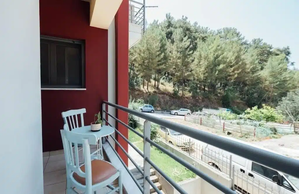 Balcony with a white table and chairs and a view of trees