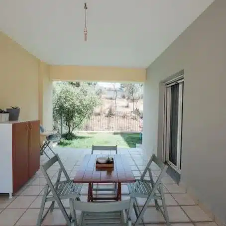 Covered terrace with a table and chairs overlooking a garden