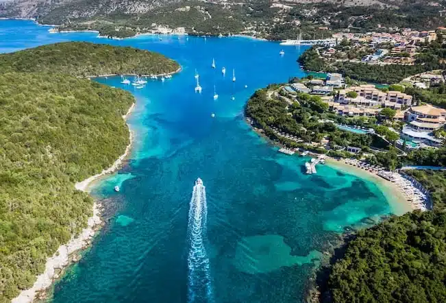 Αεροφωτογραφία του κόλπου των Συβότων με τιρκουάζ νερά, πευκόφυτα νησάκια και σκάφος