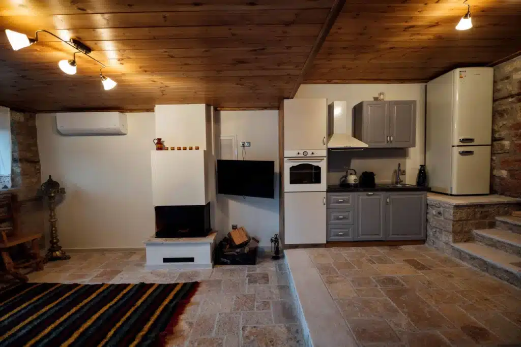 Fully equipped kitchenette with a TV and striped rug in a suite, Valaes Guesthouse, Foiniki