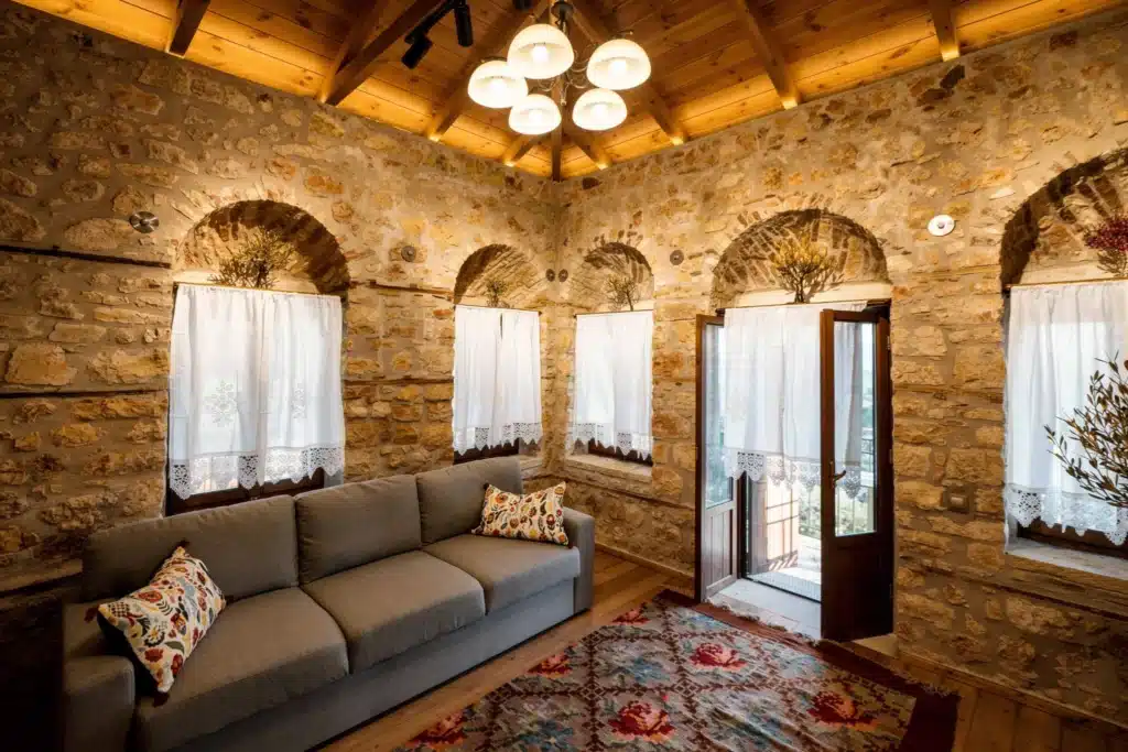 Living room with a chandelier, arched windows and a fireplace, Valaes Guesthouse, Foiniki