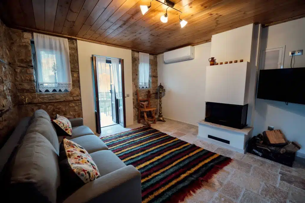 Living room with a chandelier, sofa and traditional striped rug, Valaes Guesthouse, Foiniki