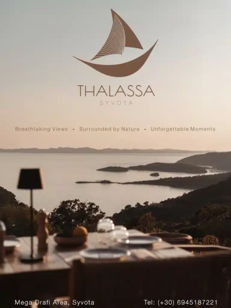 Thalassa restaurant logo above a terrace table overlooking the sea and islands at dusk