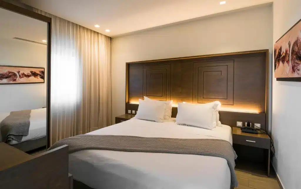 Double bed with backlit wooden headboard in a Prima Vista suite