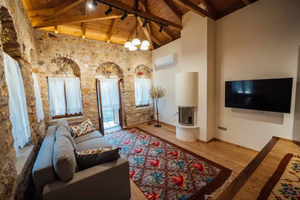 Spacious living room with arched windows, sofa and floral rug, Valaes Guesthouse, Foiniki
