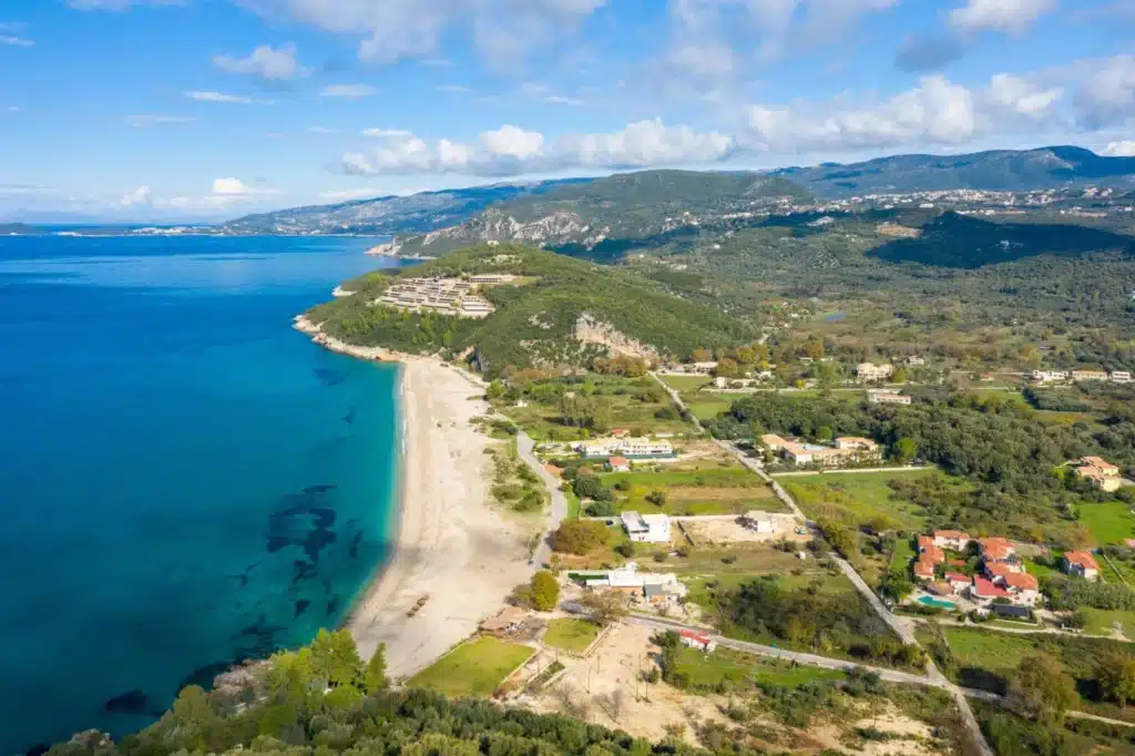 Αεροφωτογραφία μεγάλης αμμώδους παραλίας με τιρκουάζ νερά και εξοχή