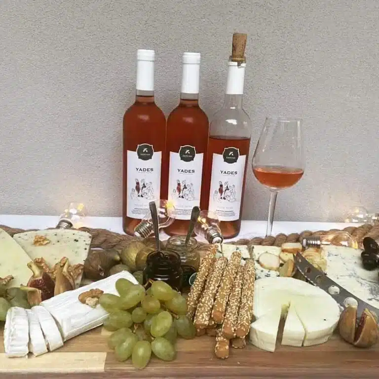 Three bottles of Zervas Winery wine on a wooden table with grapes.